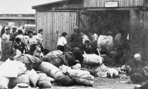 Ludzie z bagażami przed barakiem w Auschwitz. To krótkie streszczenie tego, co działo się w obozie.