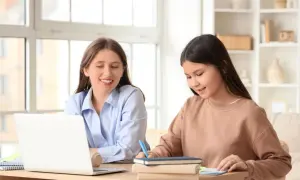 Nauczycielka z uśmiechem tłumaczy uczennicy zagadnienia gramatyczne, które stanowią dopełnienie bliższe i dalsze.