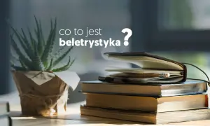 Co to jest beletrystyka? Stos książek i notes z ołówkiem, obok rośliny w doniczce.