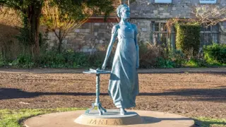 Pomnik Jane Austen, autorki słynnych powieści, stoi przy stoliku z książką.