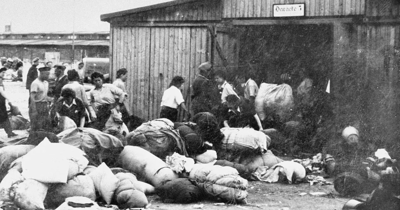 Ludzie z bagażami przed barakiem w Auschwitz. To krótkie streszczenie tego, co działo się w obozie.