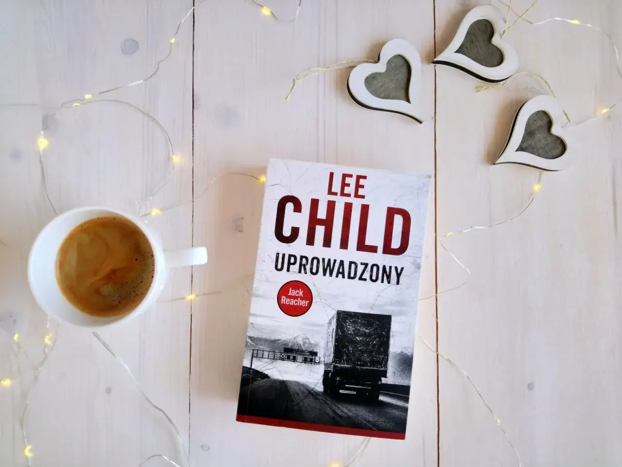 Książka "Uproszczony" Lee Child, filiżanka kawy i ozdobne serca na białym tle.