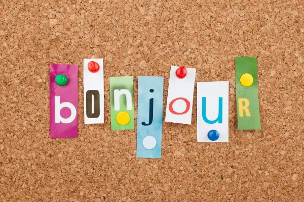 Kolorowe literki na korkowej tablicy tworzą napis "bonjour". To miłe powitanie po francusku, które może być początkiem wielu ciekawych zdań po francusku.
