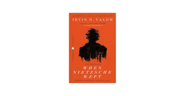 Okładka książki "Gdy Nietzsche płakał" Irvina D. Yalom z czarną sylwetką na pomarańczowym tle.